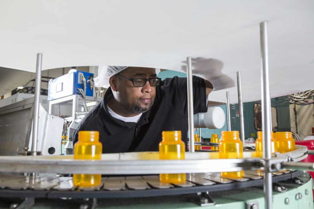 An Alphapointe team member is observing the production line in the Plastics Department.